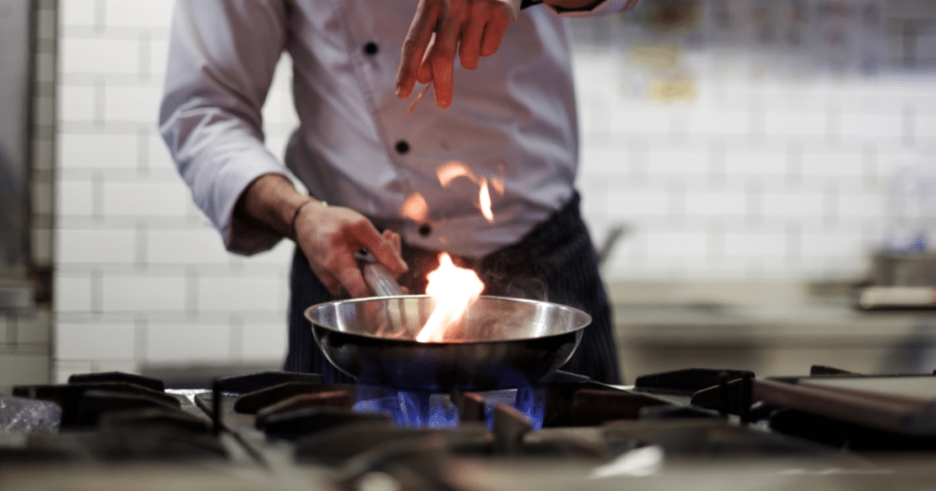 Chef cooking on a gas stovetop.